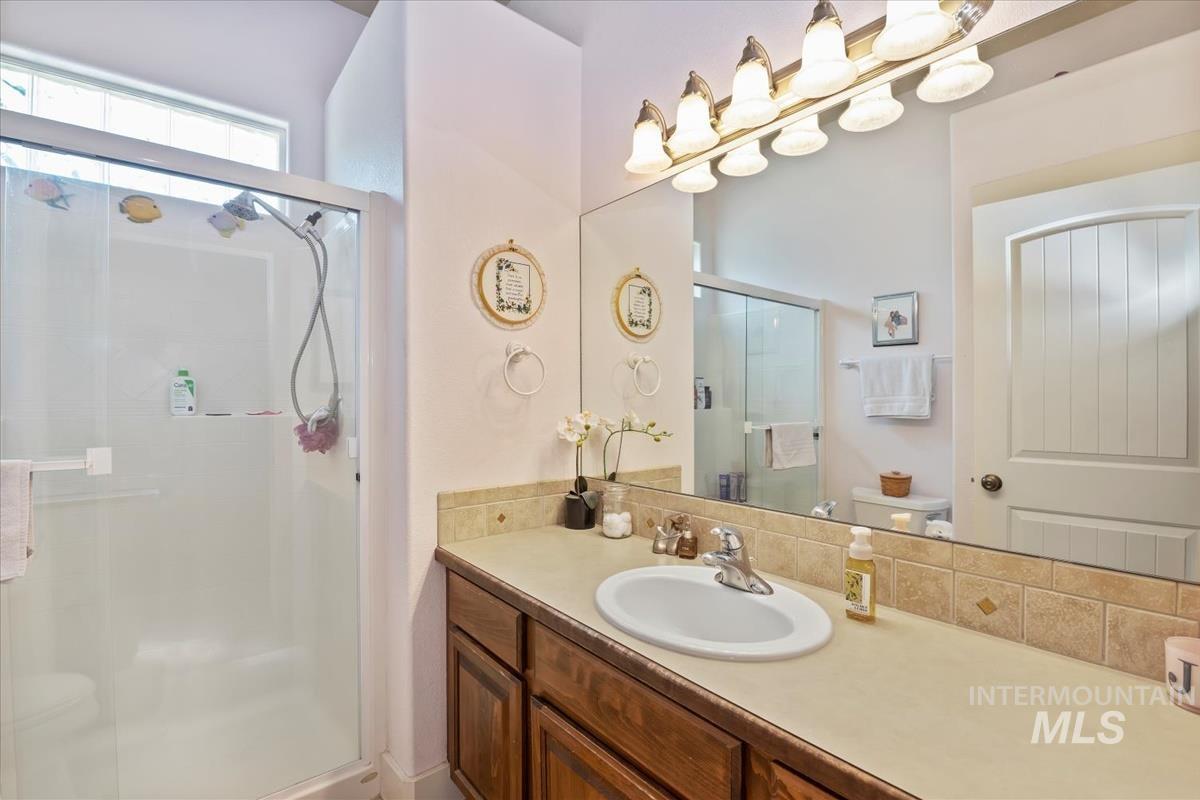 Bathroom featuring a shower stall, vanity, and decorative backsplash