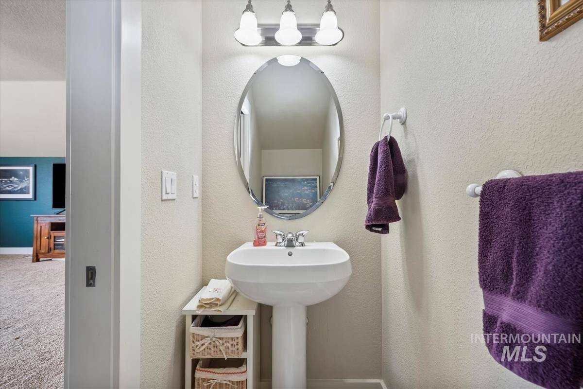 Half bathroom featuring a textured wall and baseboards