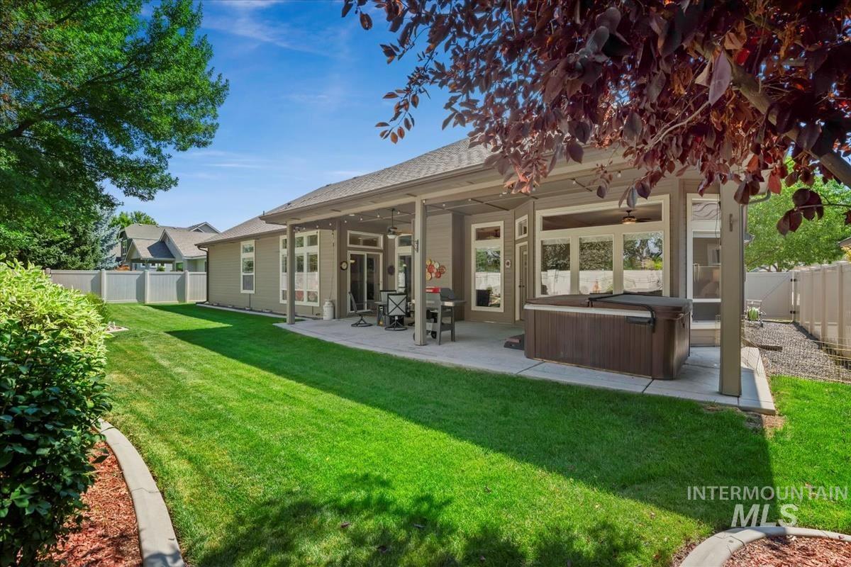 Back of property featuring a fenced backyard, a hot tub, a patio area, and ceiling fan