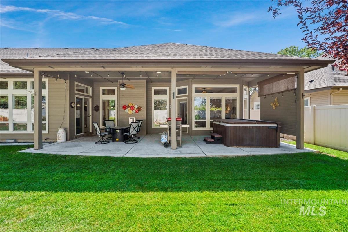 Rear view of house featuring roof with shingles, a patio, a hot tub, and ceiling fan
