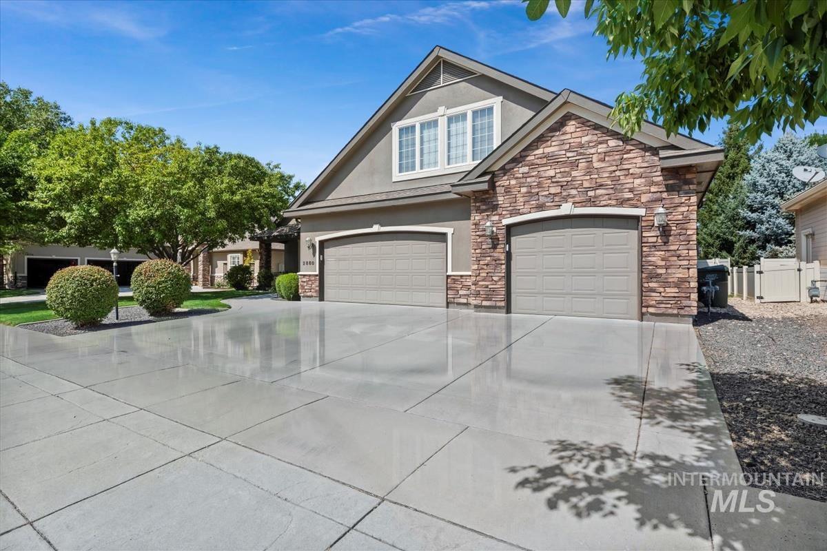 Craftsman-style home with stucco siding, concrete driveway, stone siding, and an attached garage
