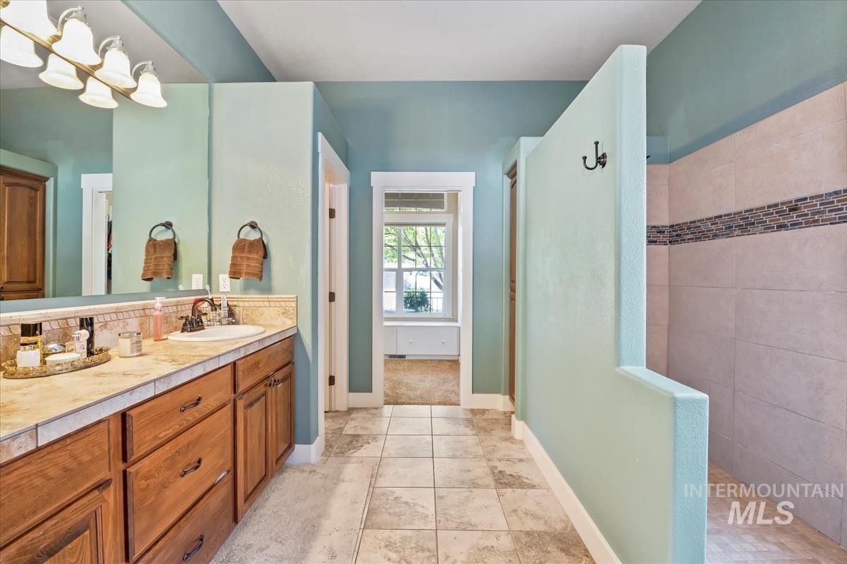 Full bath with a walk in shower, vanity, and light tile patterned floors
