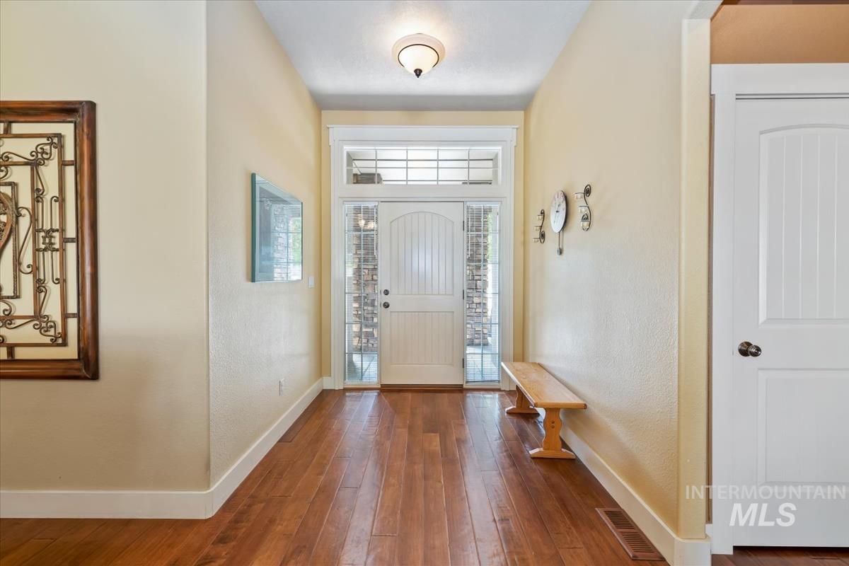 Foyer entrance with dark wood finished floors and a textured wall