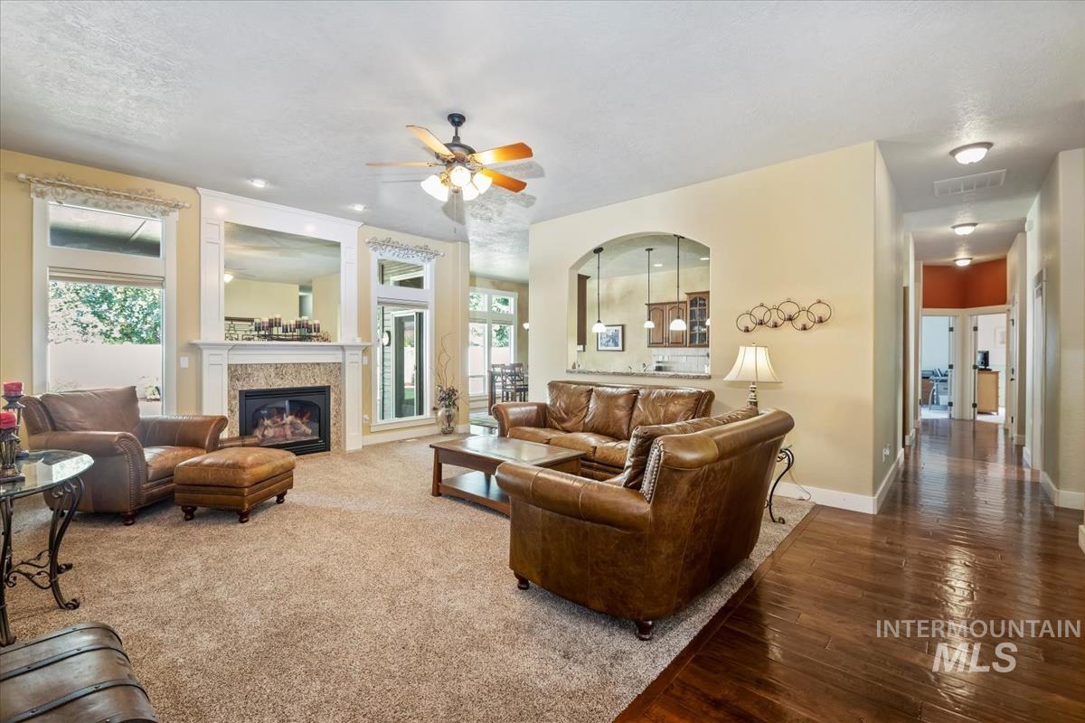 Living room with wood finished floors, ceiling fan, and a glass covered fireplace