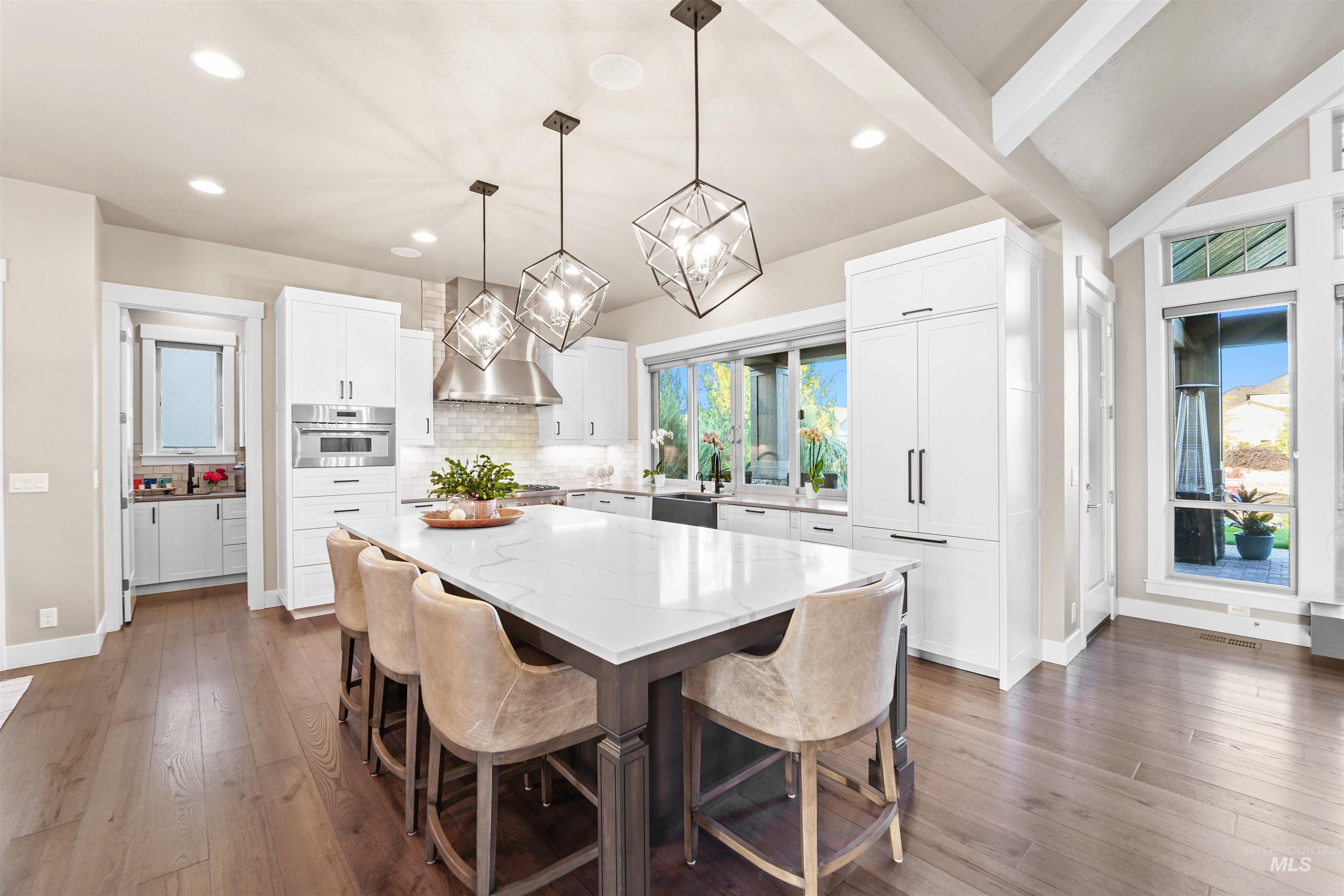 Kitchen with a kitchen breakfast bar, white cabinets, tasteful backsplash, decorative light fixtures, and a kitchen island