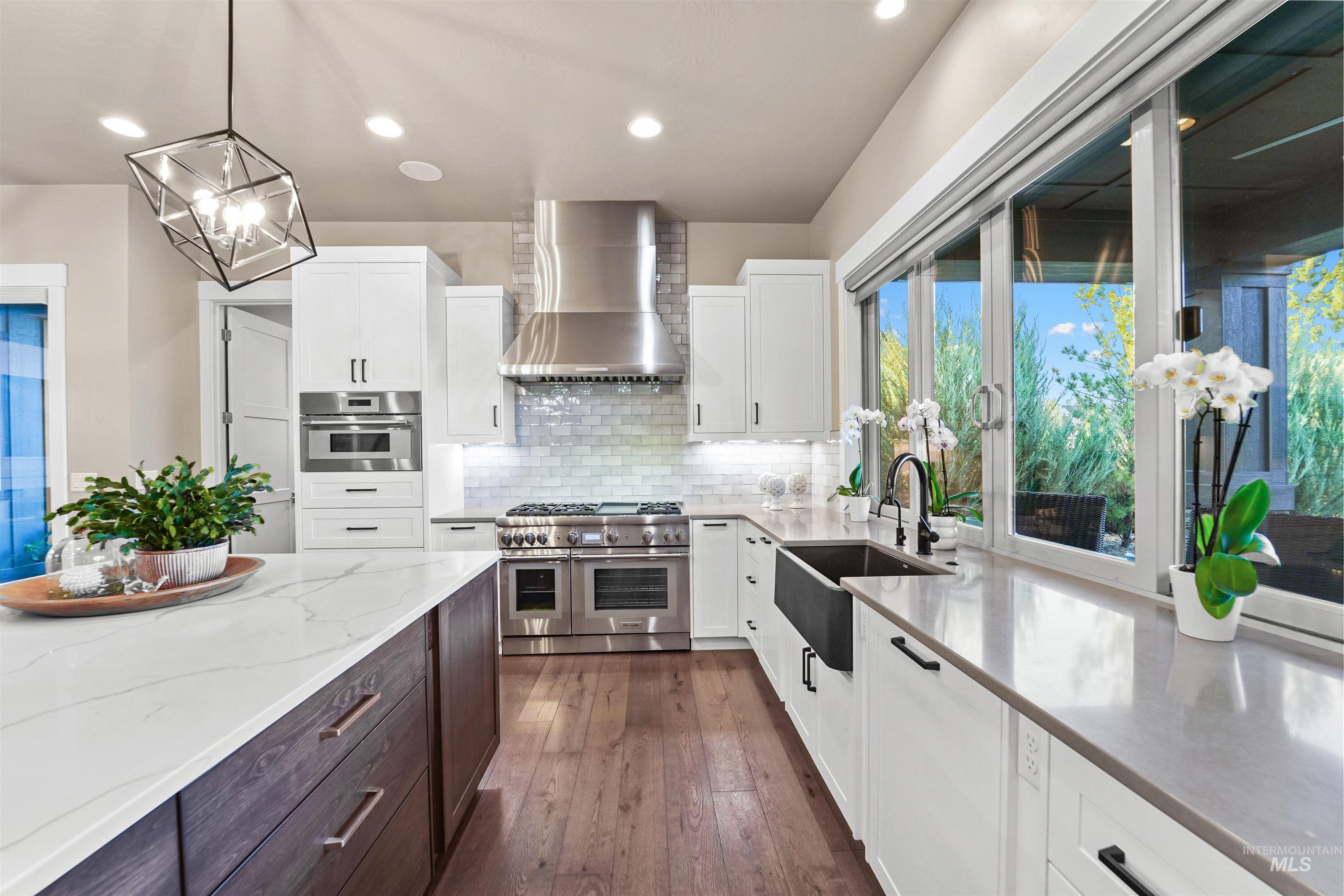 Kitchen with dark brown cabinets, white cabinetry, appliances with stainless steel finishes, light stone countertops, and recessed lighting