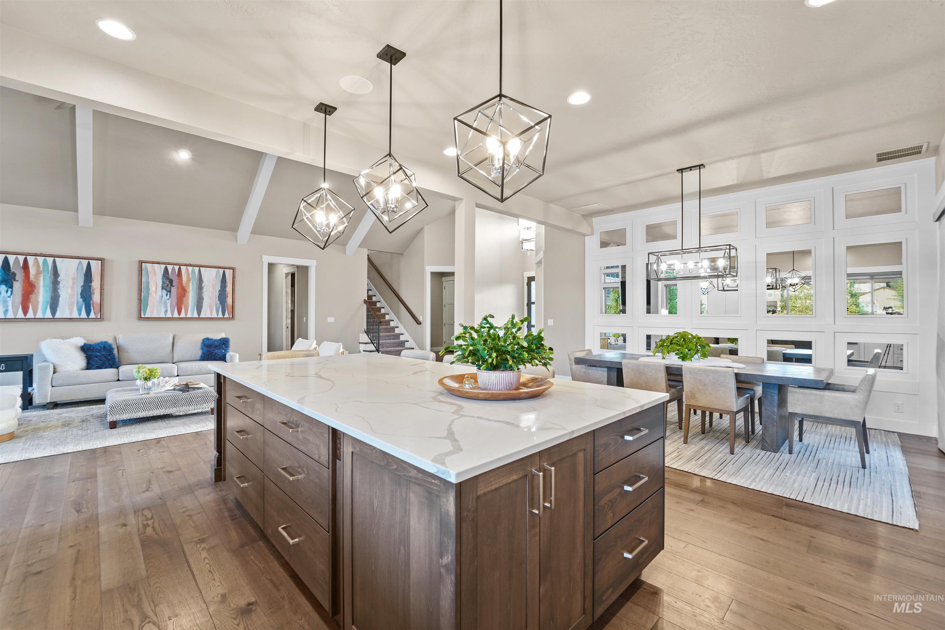 Kitchen featuring open floor plan, dark brown cabinets, hanging light fixtures, light stone countertops, and dark wood finished floors