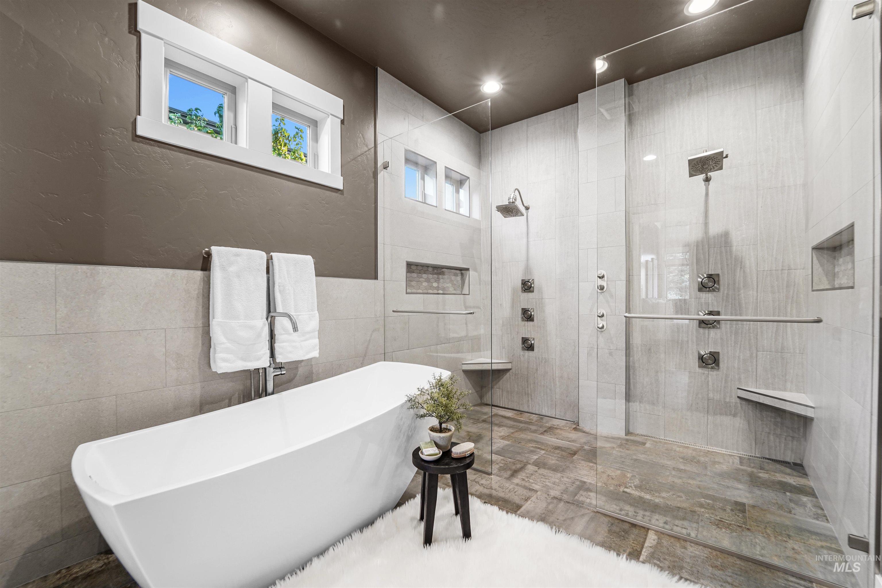 Bathroom with tile walls, a textured wall, a freestanding tub, walk in shower, and recessed lighting