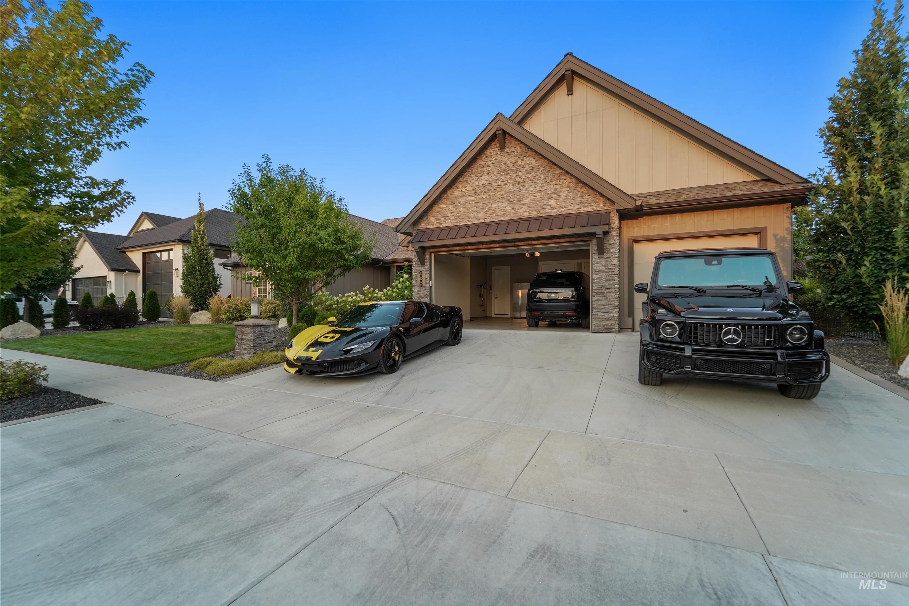 View of front facade featuring a garage, a standing seam roof, driveway, a metal roof, and stone siding