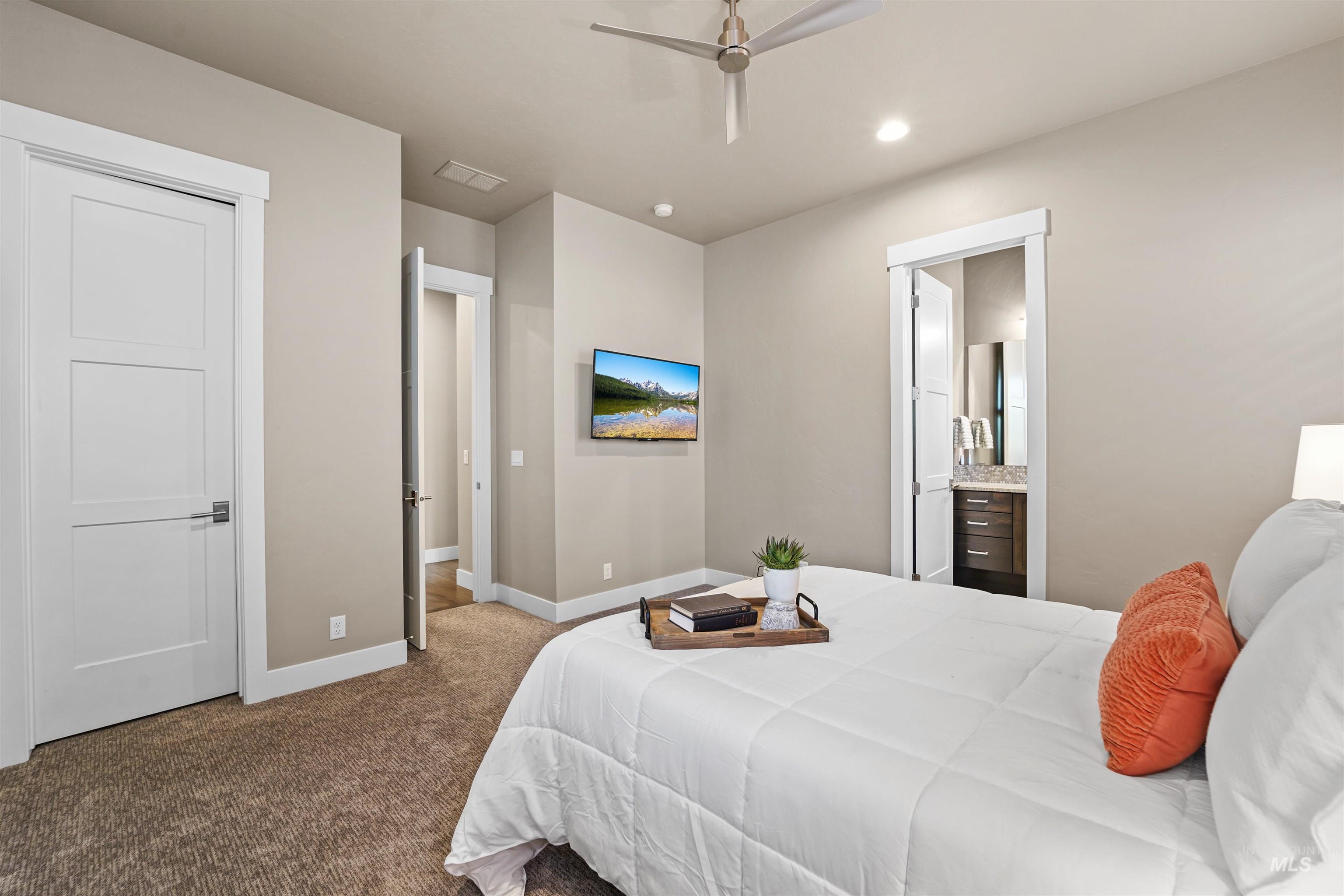 Bedroom with dark colored carpet, ensuite bath, recessed lighting, and a ceiling fan