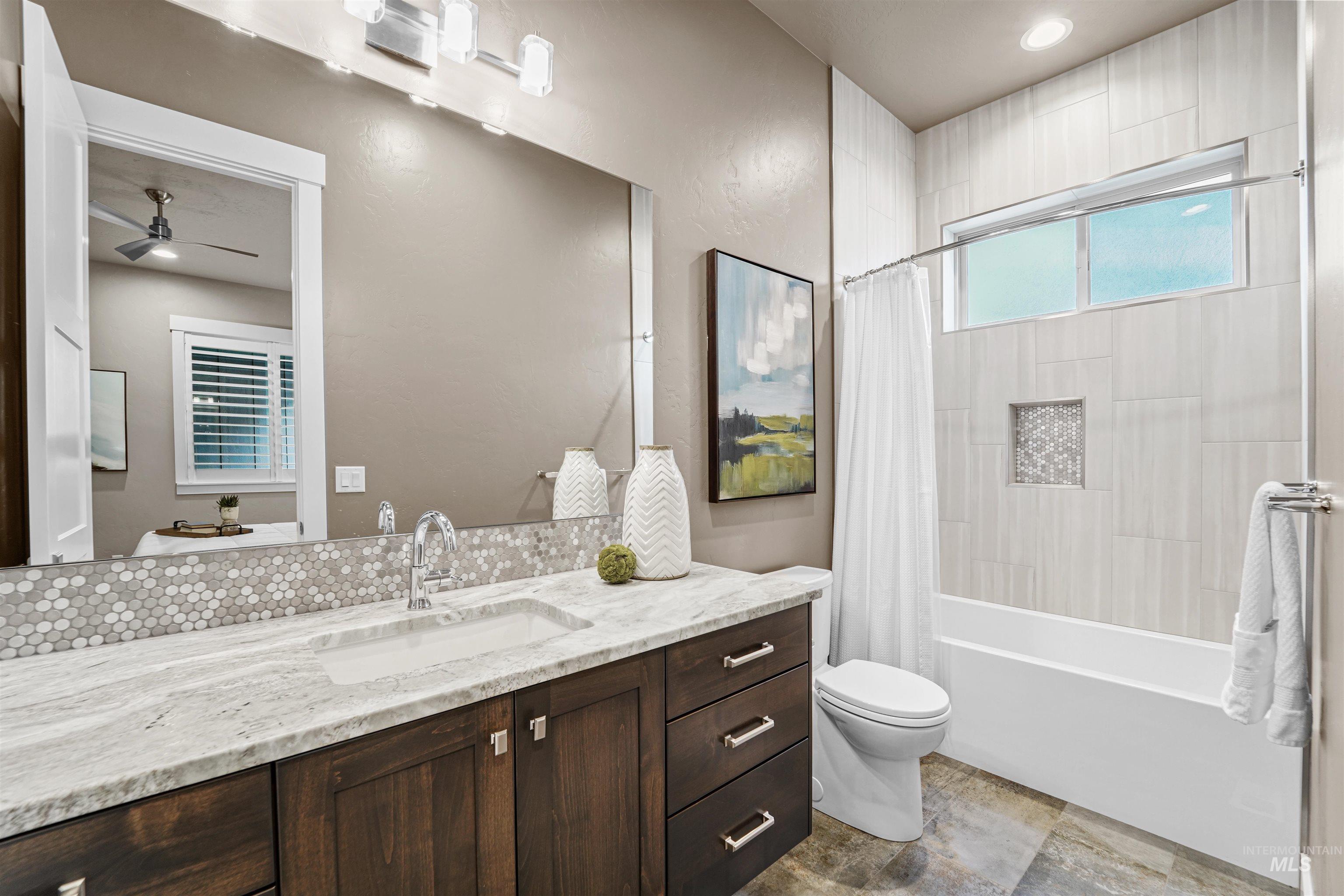 Bathroom featuring shower / bath combination with curtain, vanity, and a ceiling fan