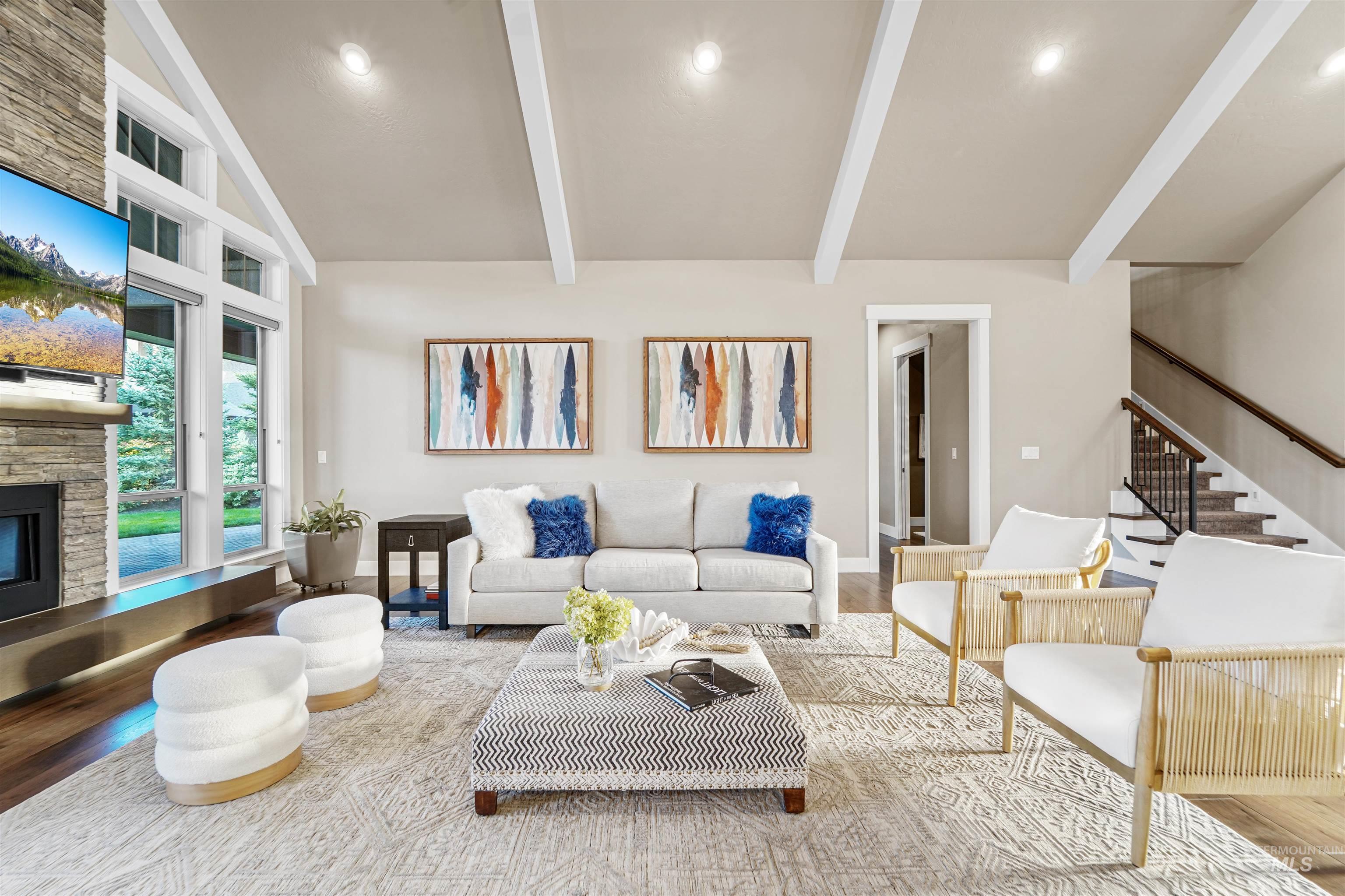 Living area with wood finished floors, a stone fireplace, recessed lighting, and stairway