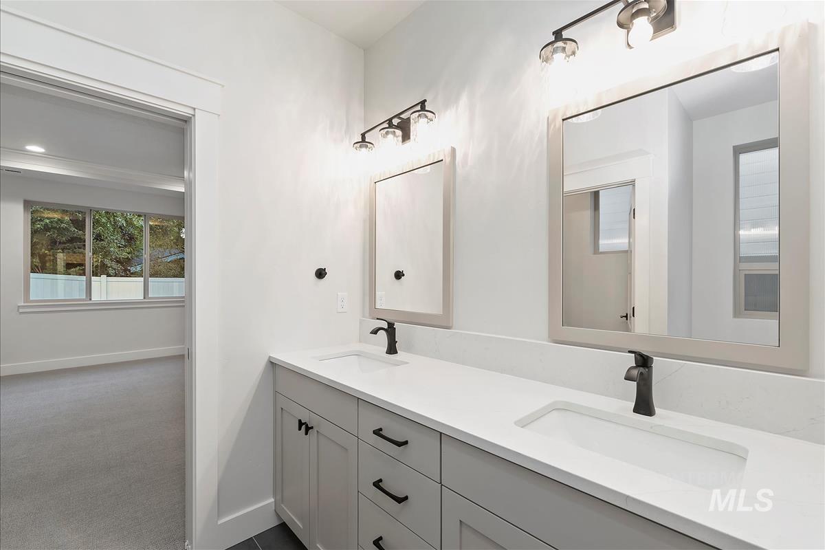 Full bath featuring double vanity and baseboards