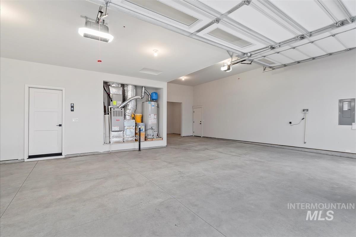 Garage featuring electric panel, heating unit, gas water heater, and a garage door opener