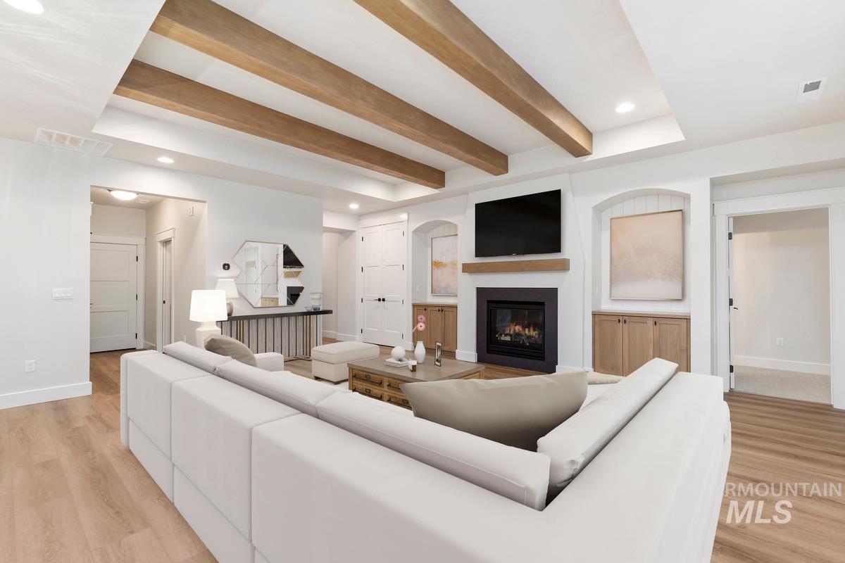 Living area with recessed lighting, light wood-type flooring, a glass covered fireplace, and beamed ceiling