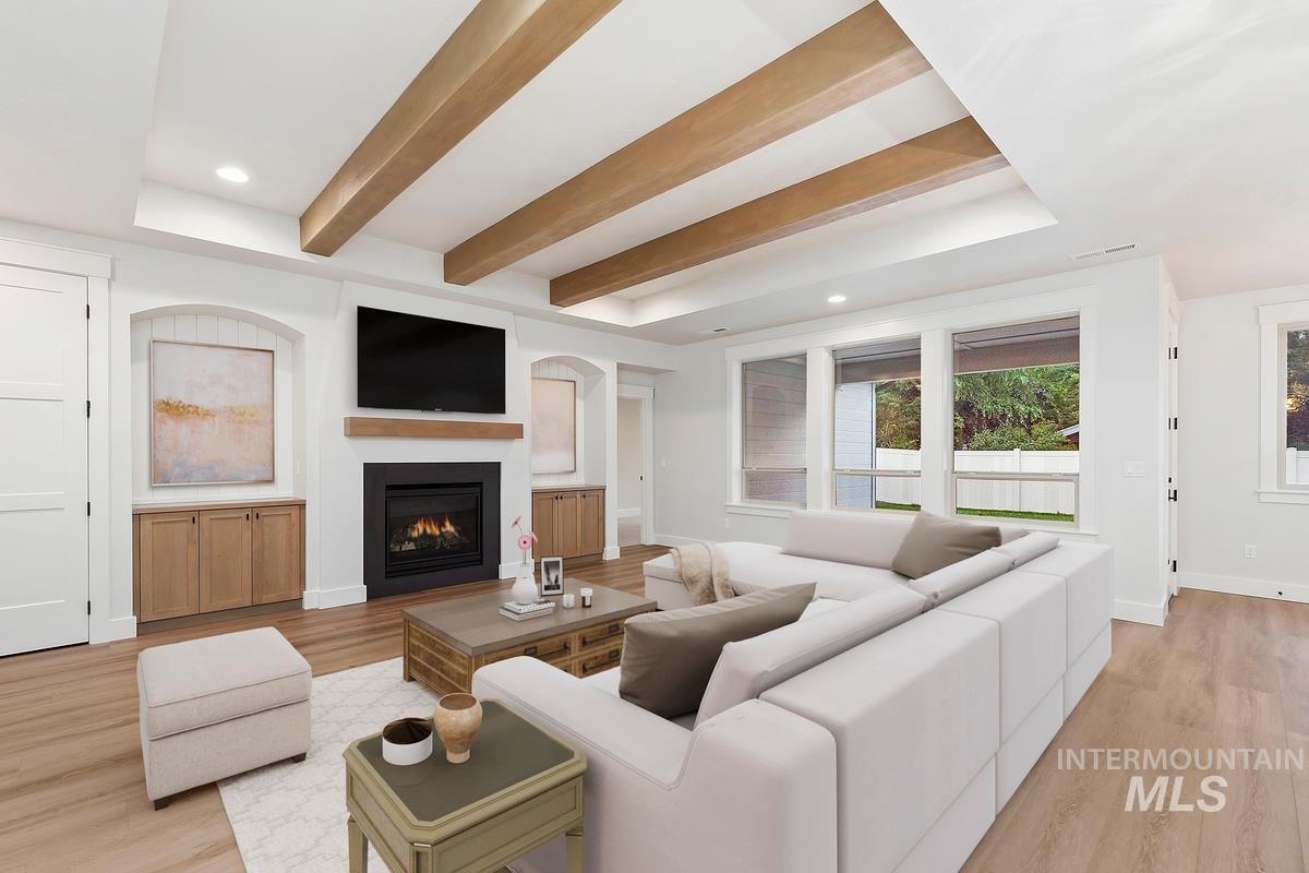 Living area featuring light wood-style floors, beamed ceiling, a warm lit fireplace, and recessed lighting
