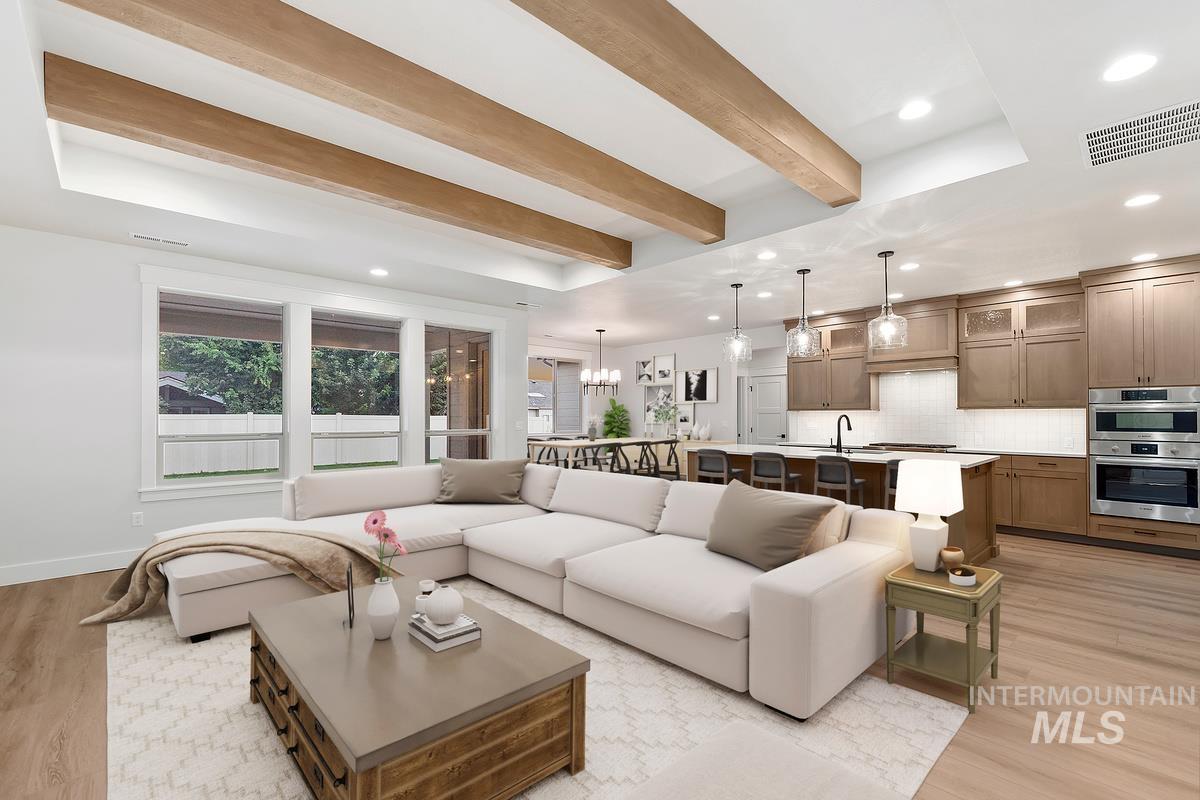 Living area with light wood-type flooring, recessed lighting, beamed ceiling, and a raised ceiling