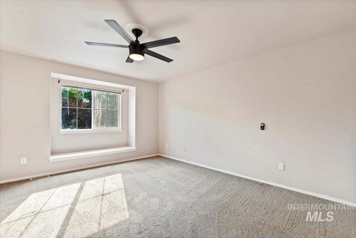 Carpeted empty room featuring baseboards and ceiling fan