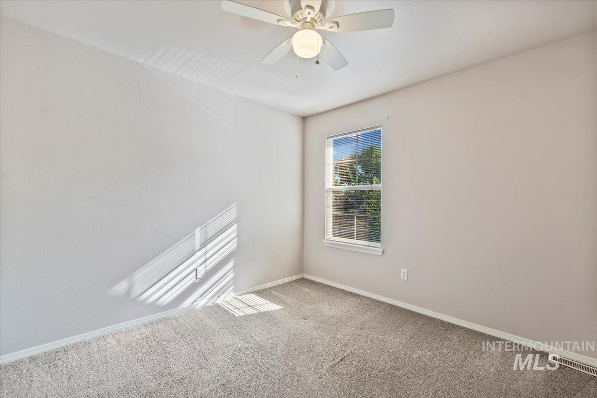 Carpeted spare room with baseboards and a ceiling fan