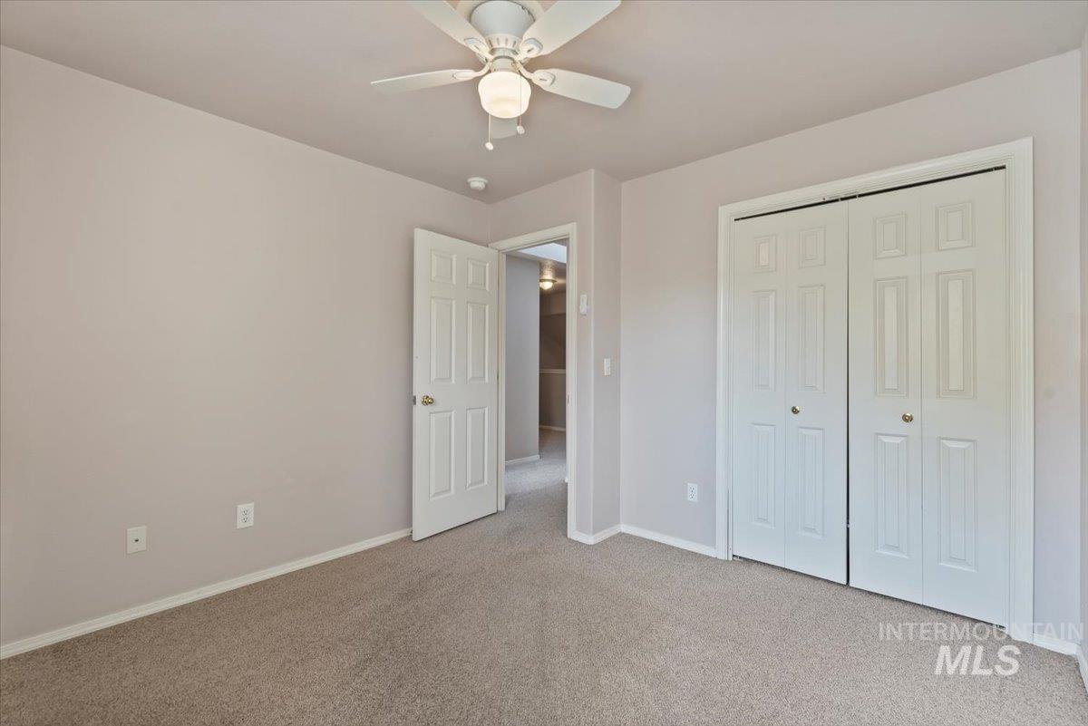 Unfurnished bedroom featuring light colored carpet, a ceiling fan, and a closet