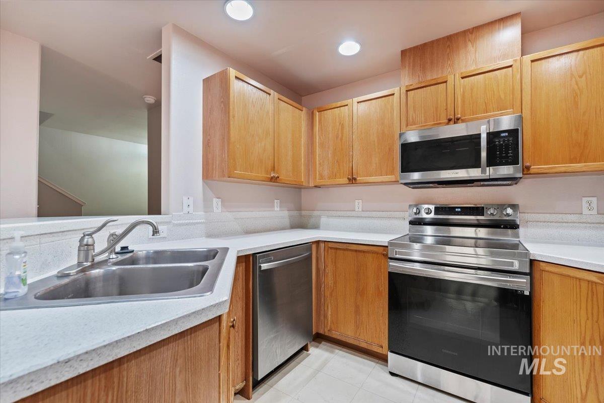 Kitchen with stainless steel appliances, light tile patterned flooring, recessed lighting, and light brown cabinets