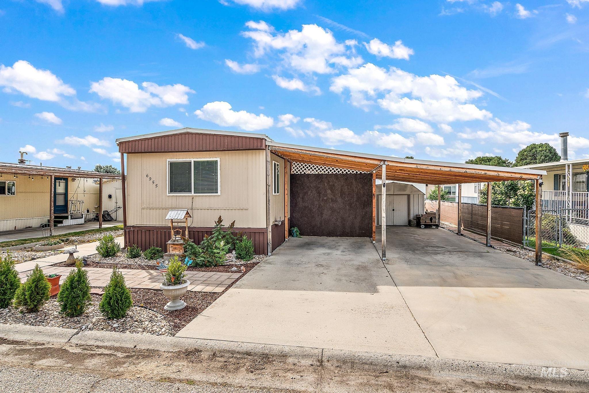 Manufactured / mobile home with a carport, an outdoor structure, and concrete driveway