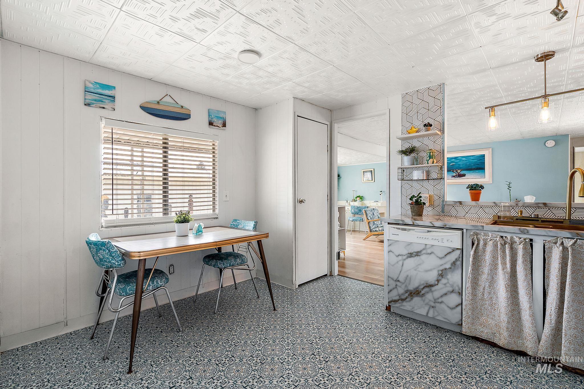 Kitchen featuring dishwasher, open shelves, pendant lighting, and wooden walls