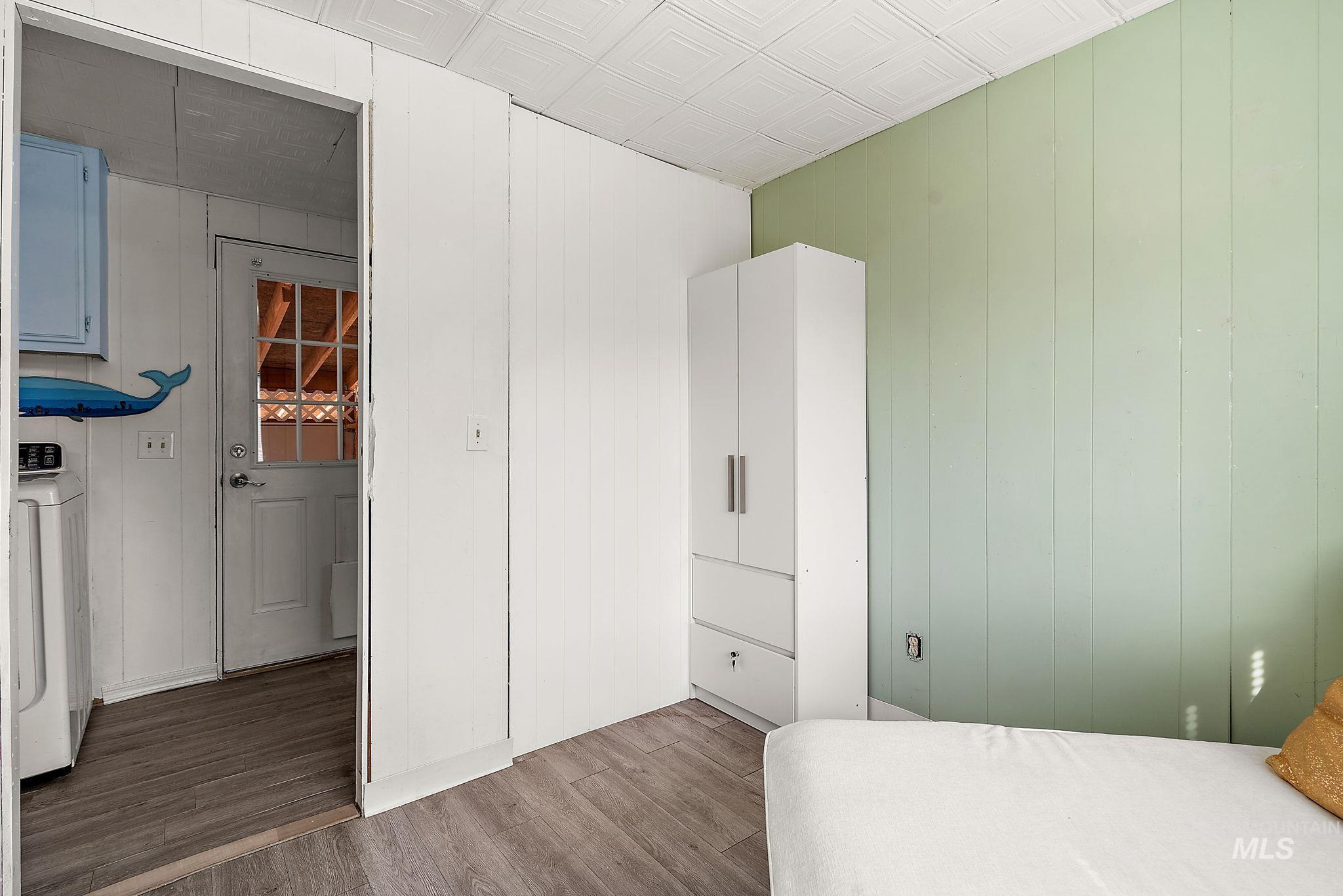 Bedroom featuring wood finished floors, wooden walls, and washer / clothes dryer