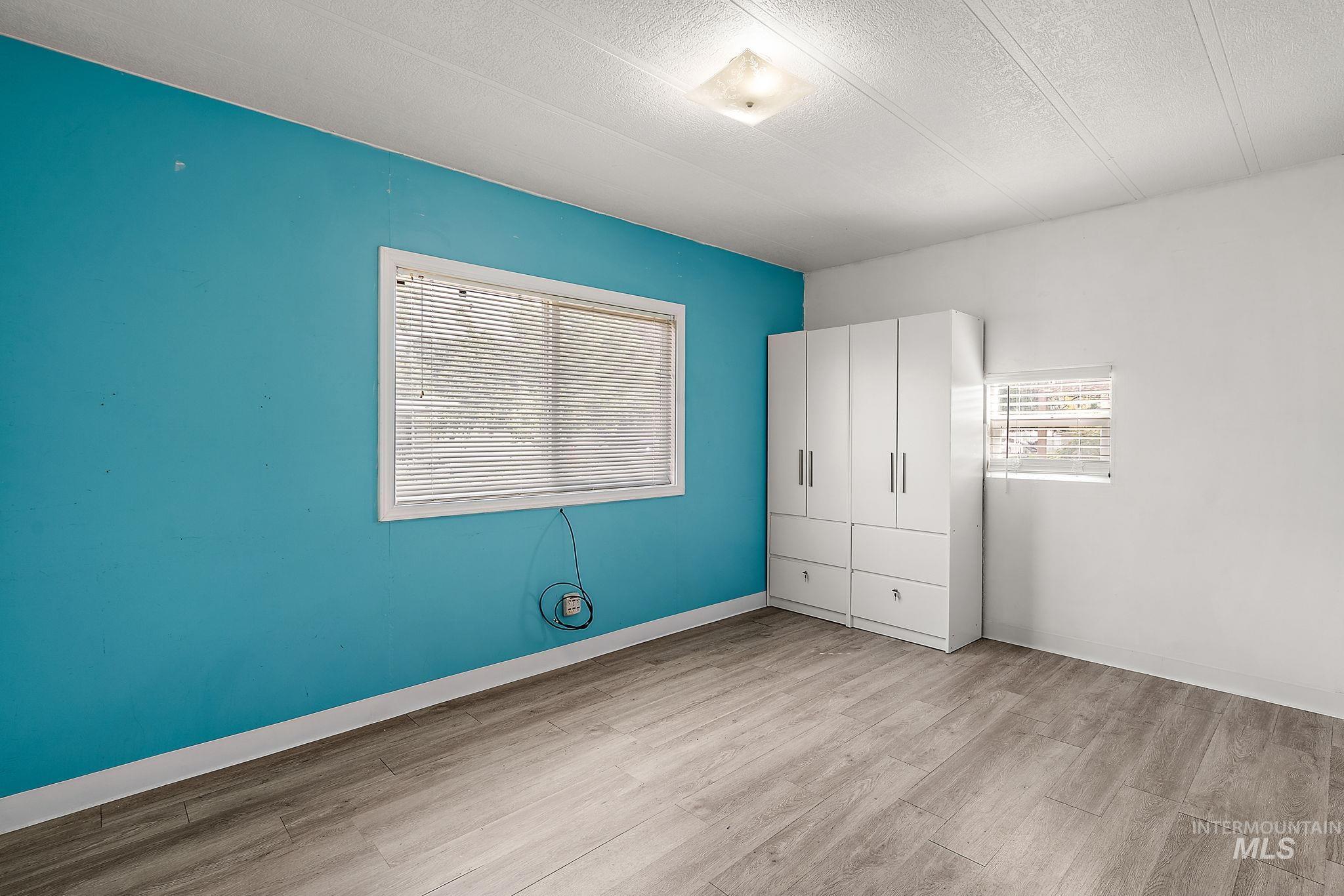 Unfurnished bedroom with light wood-type flooring and a textured ceiling