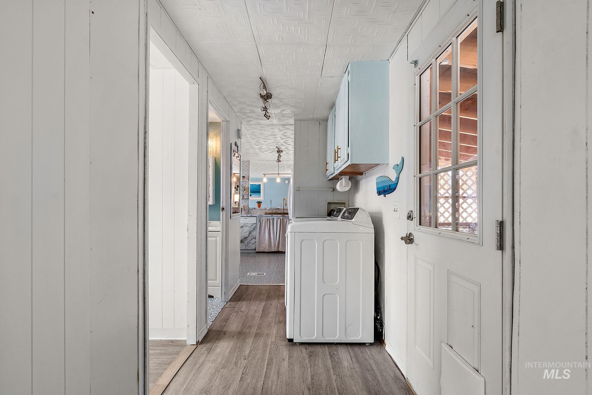 Laundry area featuring light wood-style floors, washer / clothes dryer, and cabinet space