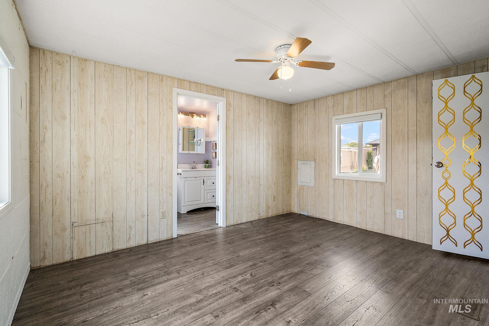 Master Bedroom featuring dark wood-style floors, wood walls, and ceiling fan