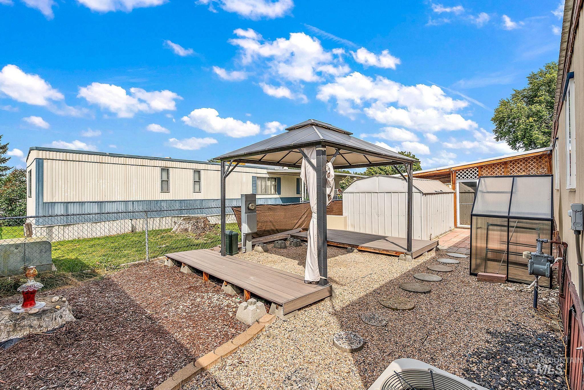 View of yard featuring a wooden deck, an outdoor structure, an exterior structure, and a gazebo
