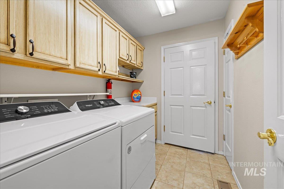Washroom featuring light tile patterned flooring, cabinet space, and washer and dryer