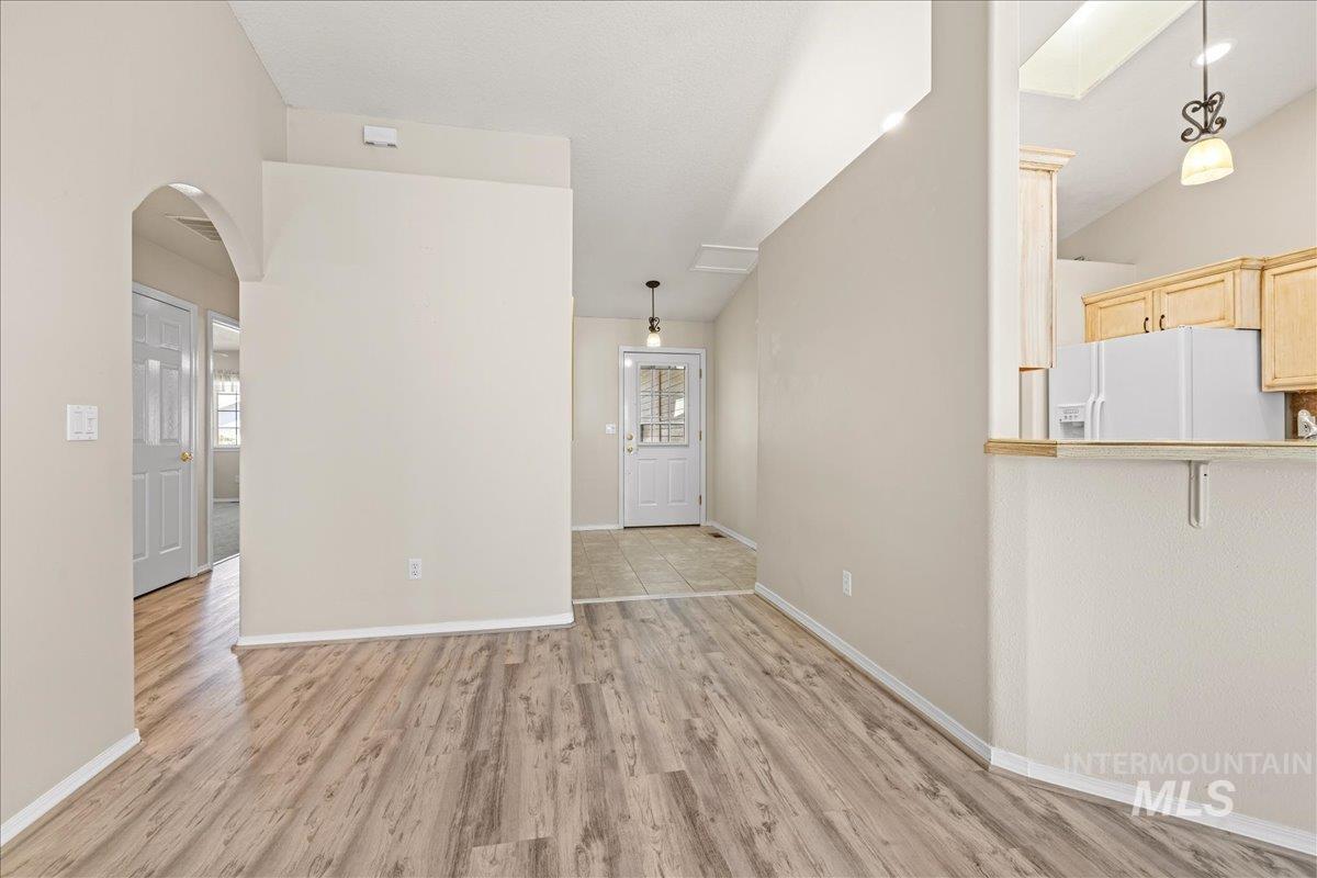 Unfurnished living room with light wood-style floors and arched walkways