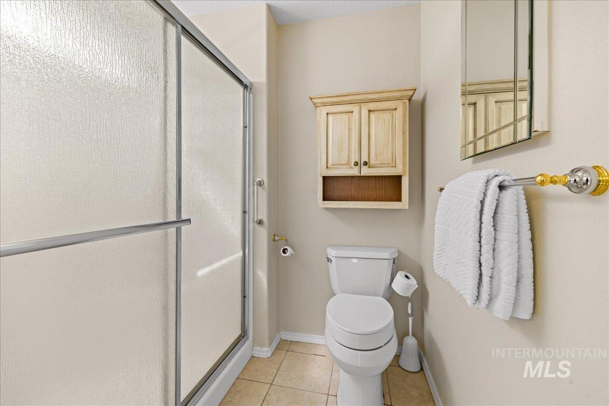 Bathroom featuring light tile patterned floors and a shower stall