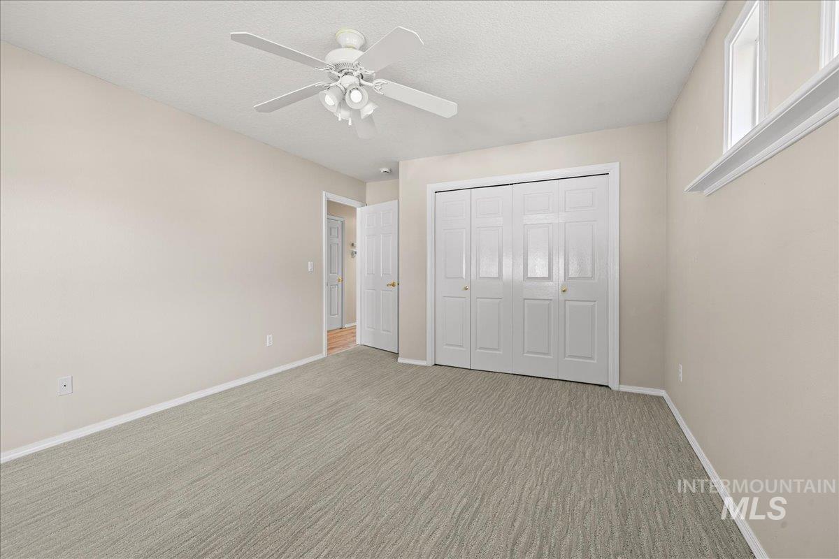 Unfurnished bedroom with carpet, ceiling fan, a closet, and a textured ceiling