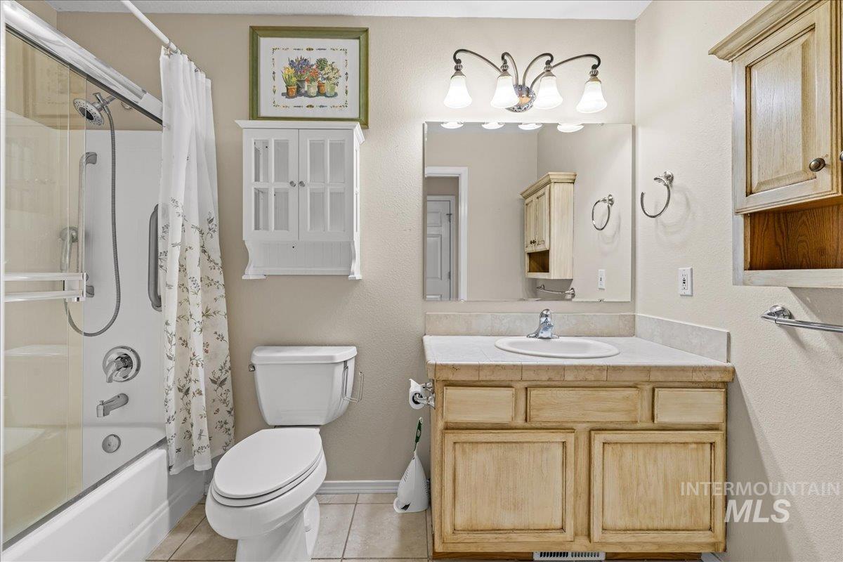 Full bathroom featuring shower / bath combo, light tile patterned flooring, vanity, and a textured wall