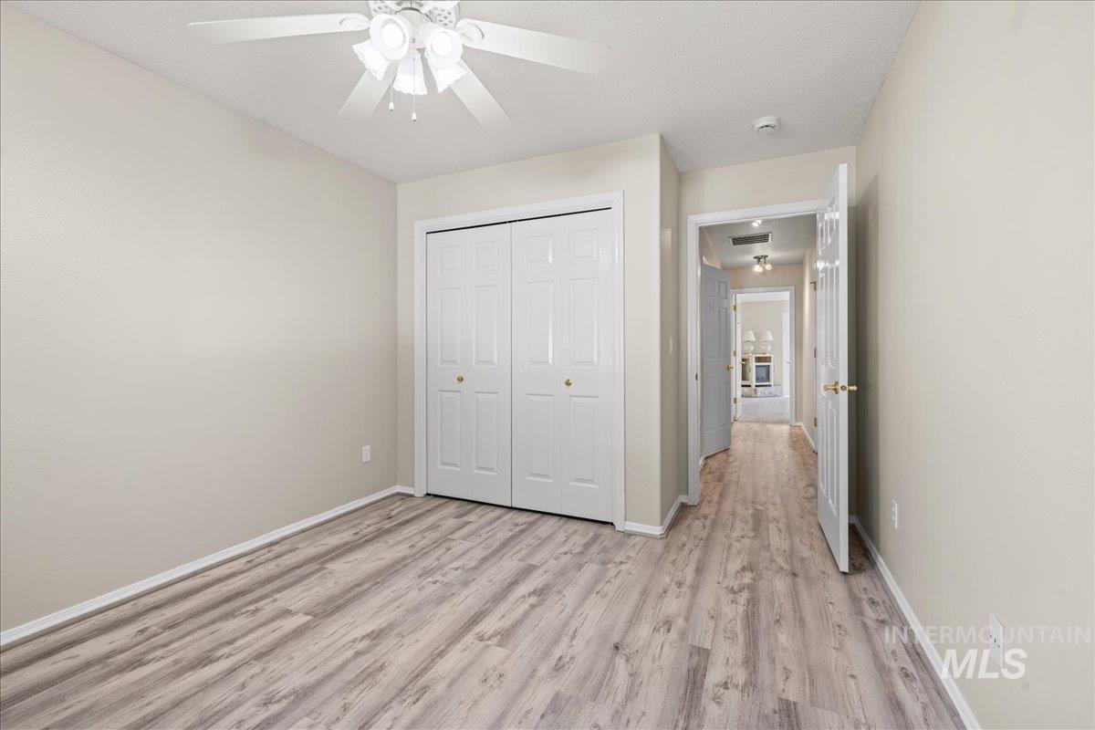 Unfurnished bedroom featuring light wood-style floors, a closet, and a ceiling fan