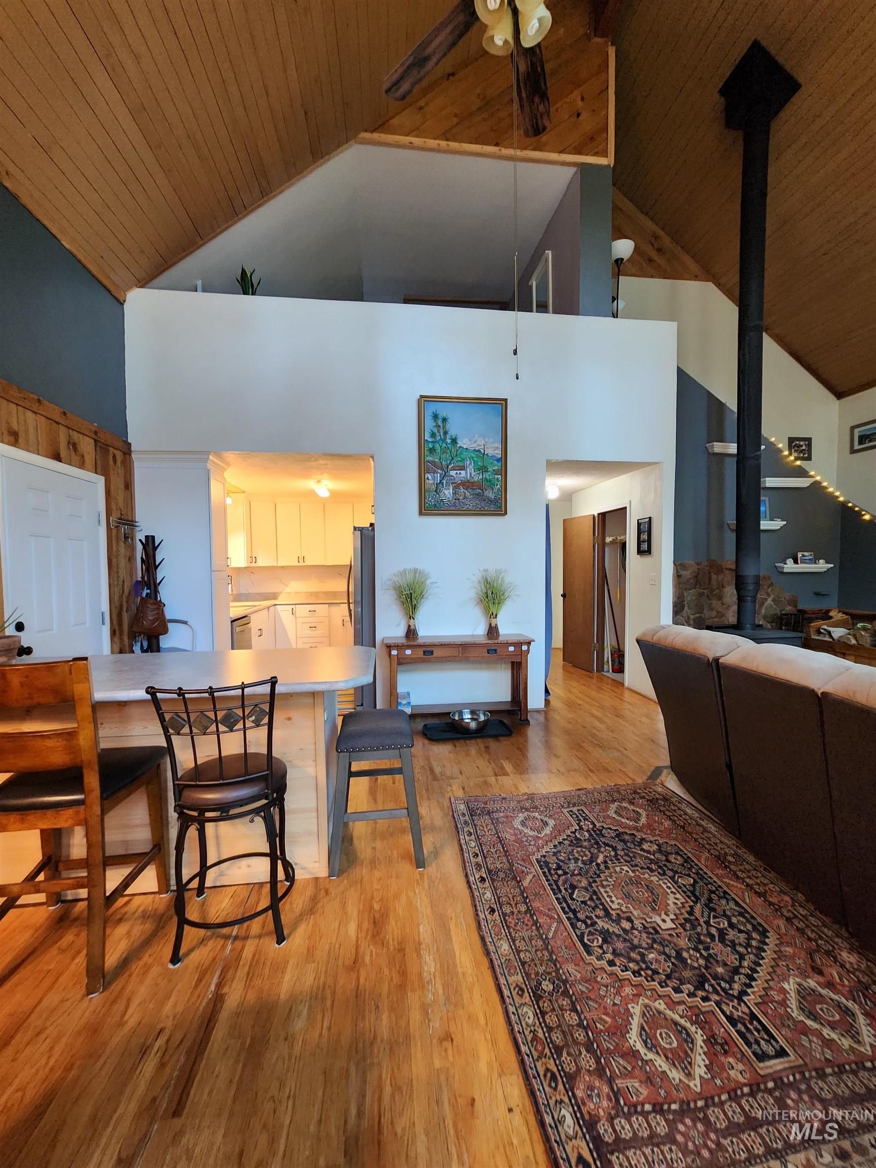Kitchen with a kitchen breakfast bar, light countertops, a ceiling fan, light wood-style floors, and a wood stove