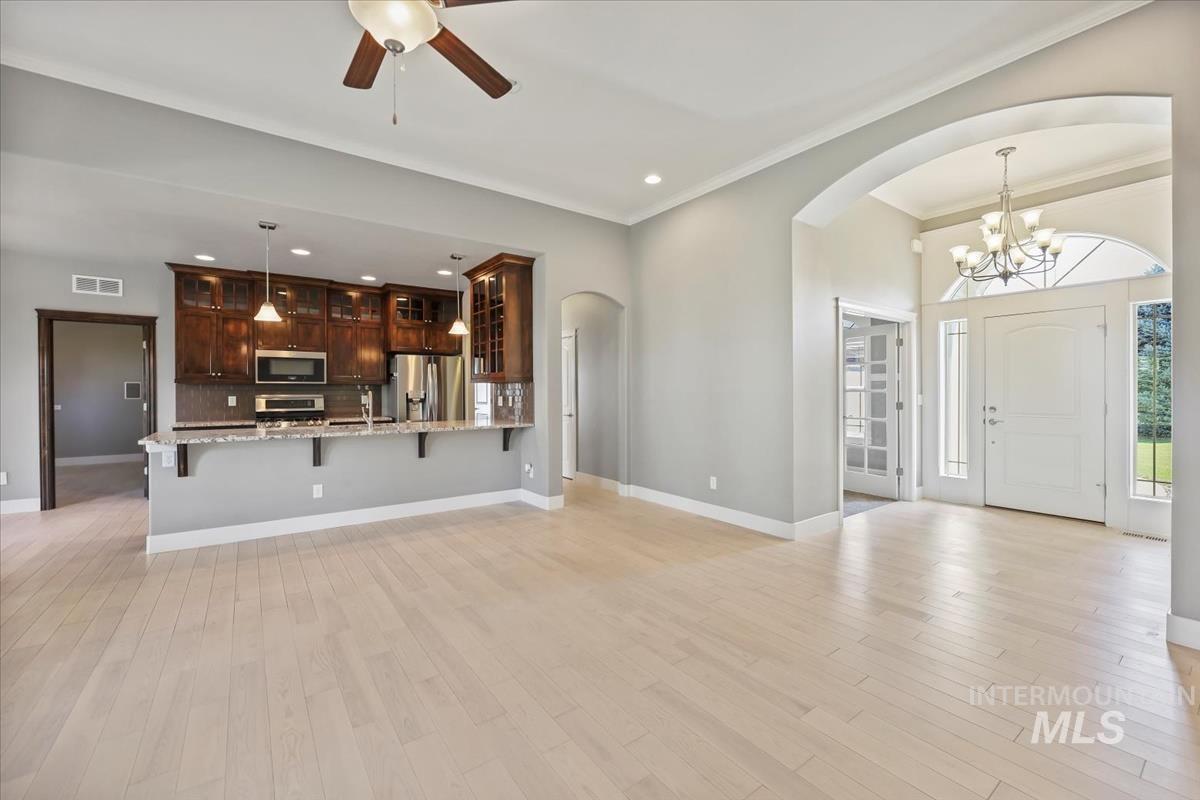 Unfurnished living room featuring arched walkways, light wood-style floors, a chandelier, recessed lighting, and ceiling fan