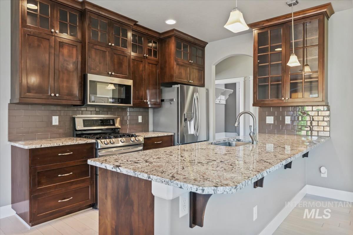 Kitchen with glass insert cabinets, tasteful backsplash, light stone counters, and recessed lighting