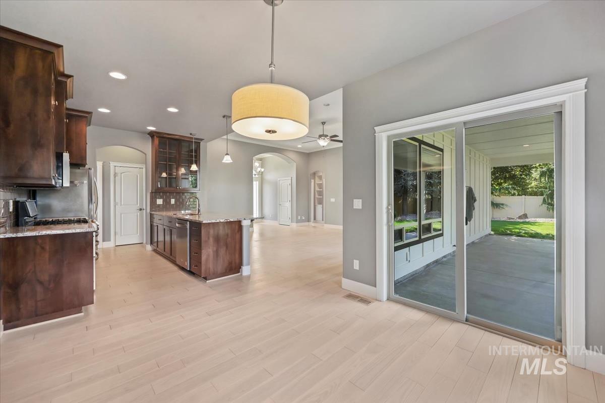 Kitchen with glass insert cabinets, light stone countertops, recessed lighting, tasteful backsplash, and open floor plan