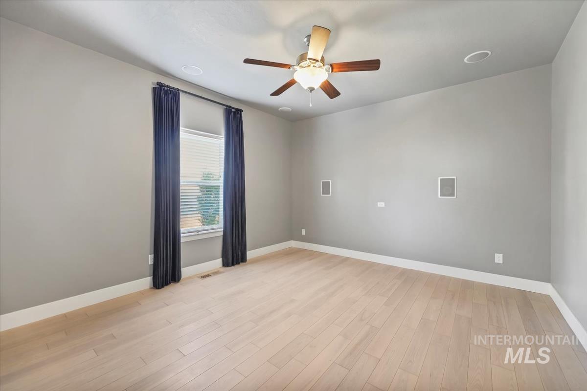 Empty room featuring light wood finished floors, built in surround sound, and ceiling fan