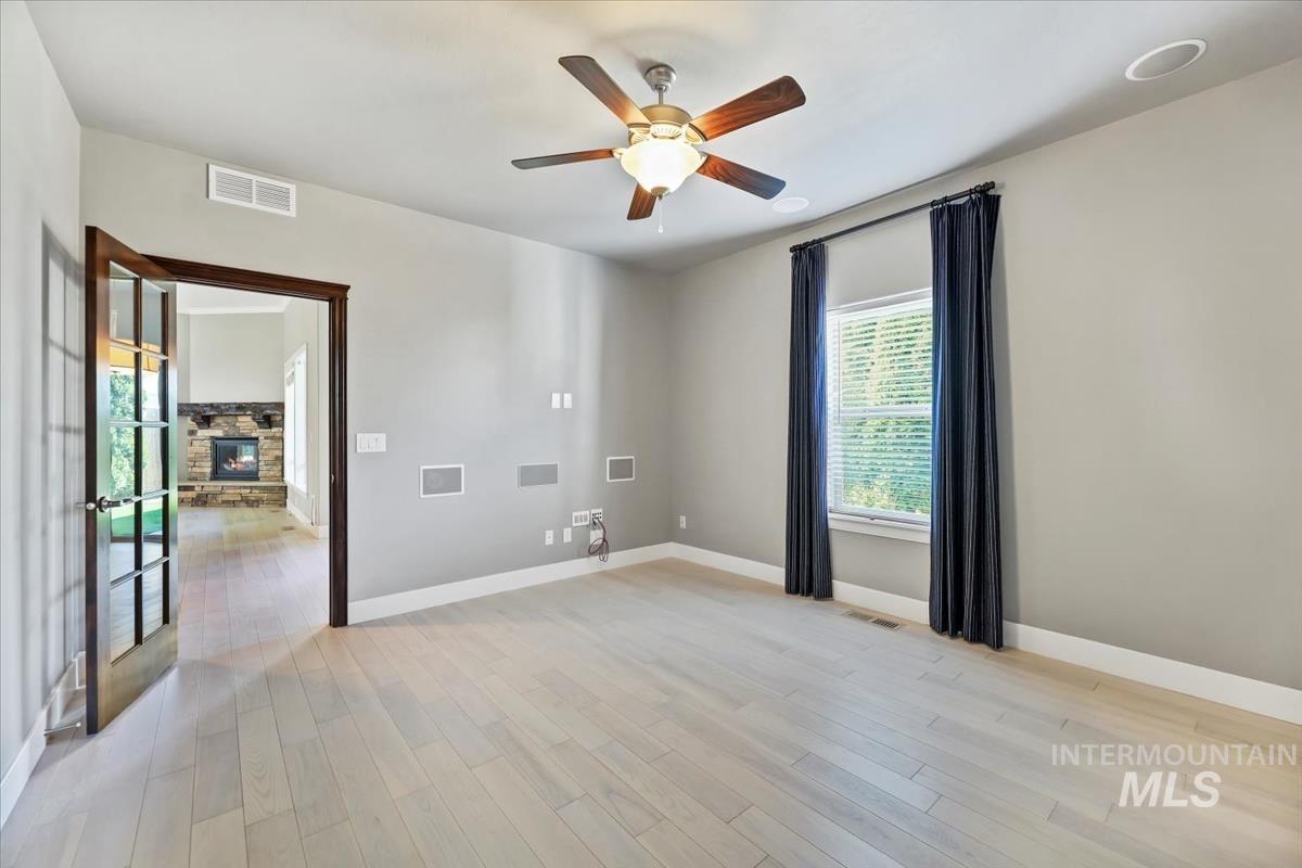 Spare room with light wood-style floors, built in surround sound, and a ceiling fan