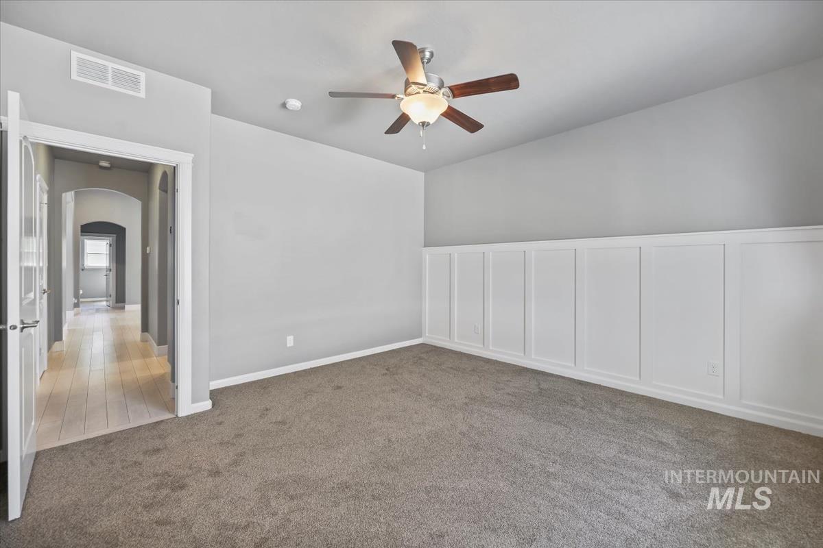 Master Bedroom with ceiling fan, arched walkways, and light carpet