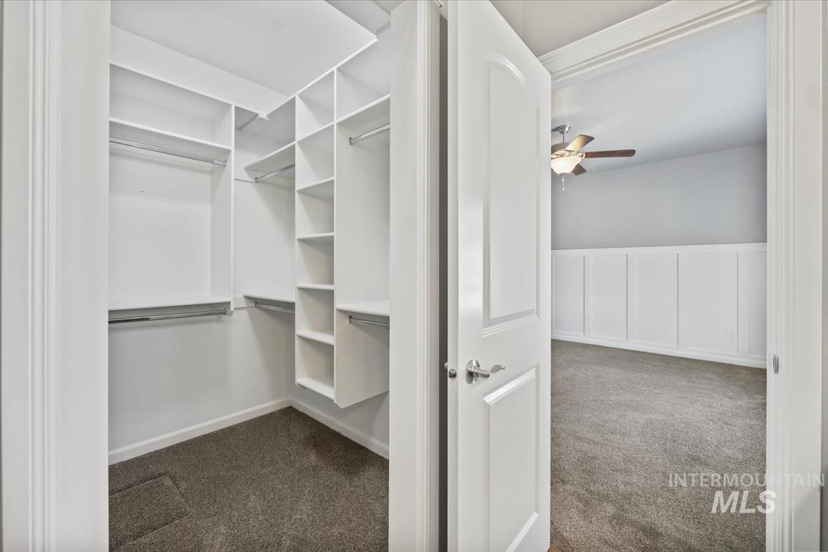 Spacious closet featuring dark carpet and ceiling fan