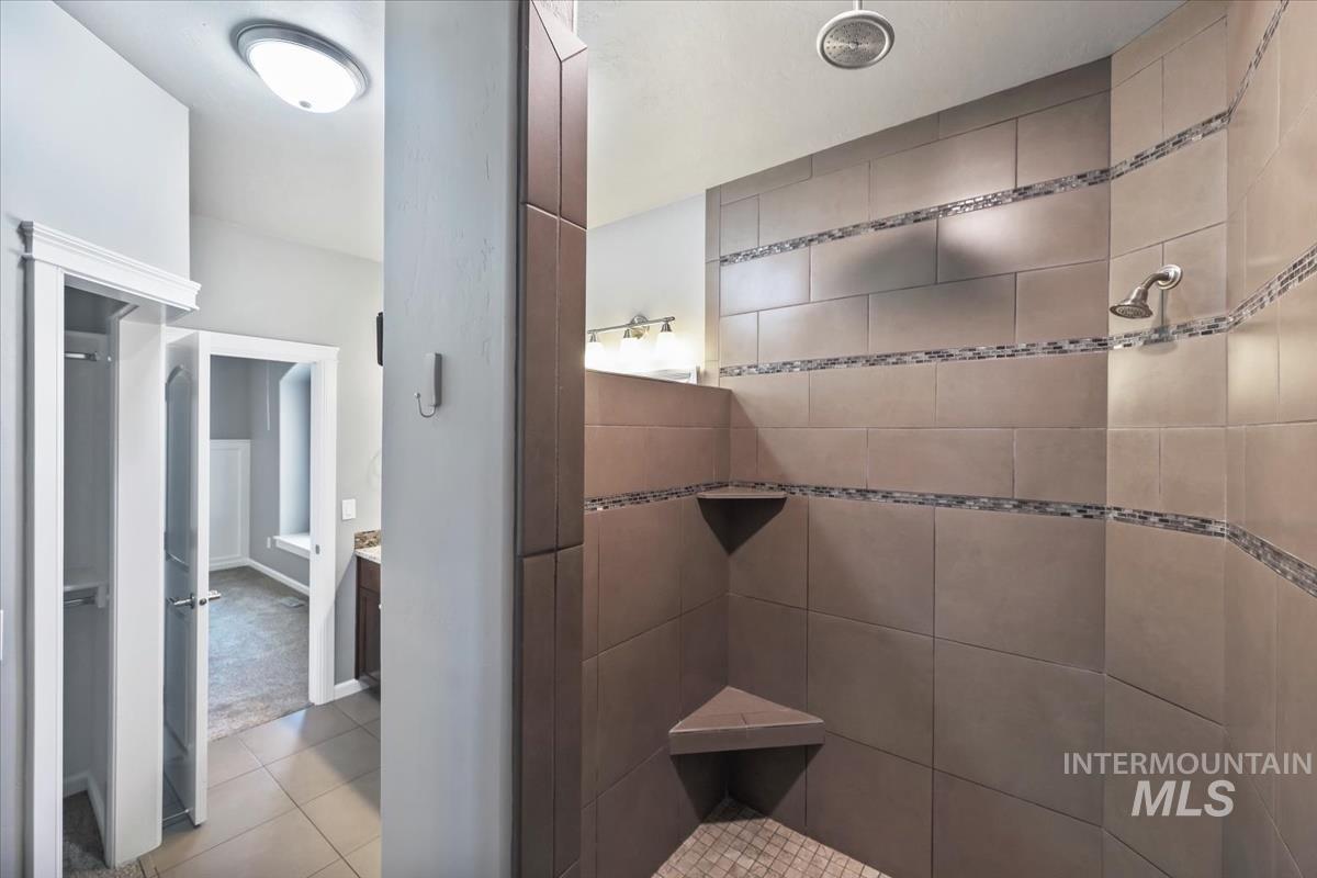 Bathroom with a walk in shower, light tile patterned flooring, and vanity