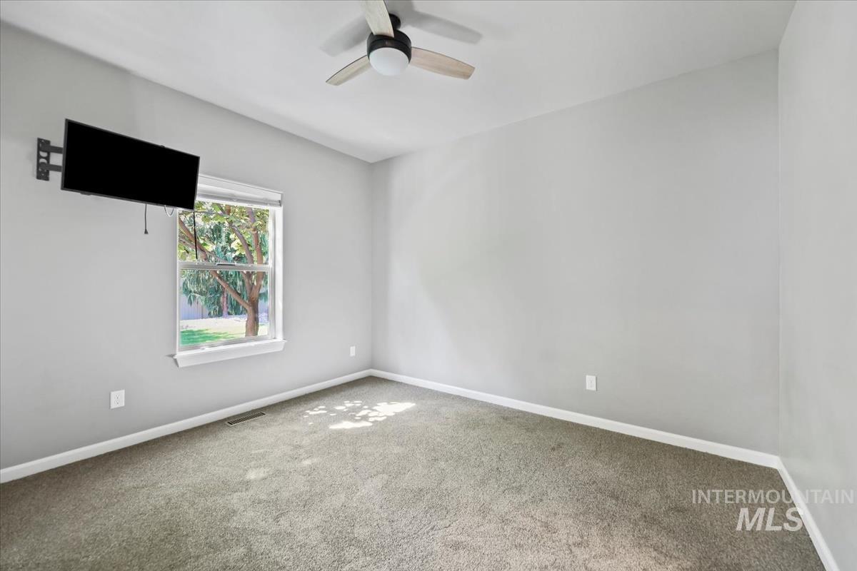 Carpeted spare room with baseboards and ceiling fan