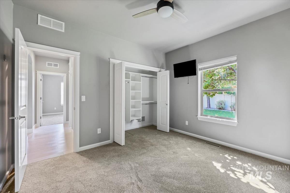 Unfurnished bedroom with light colored carpet, a closet, and a ceiling fan