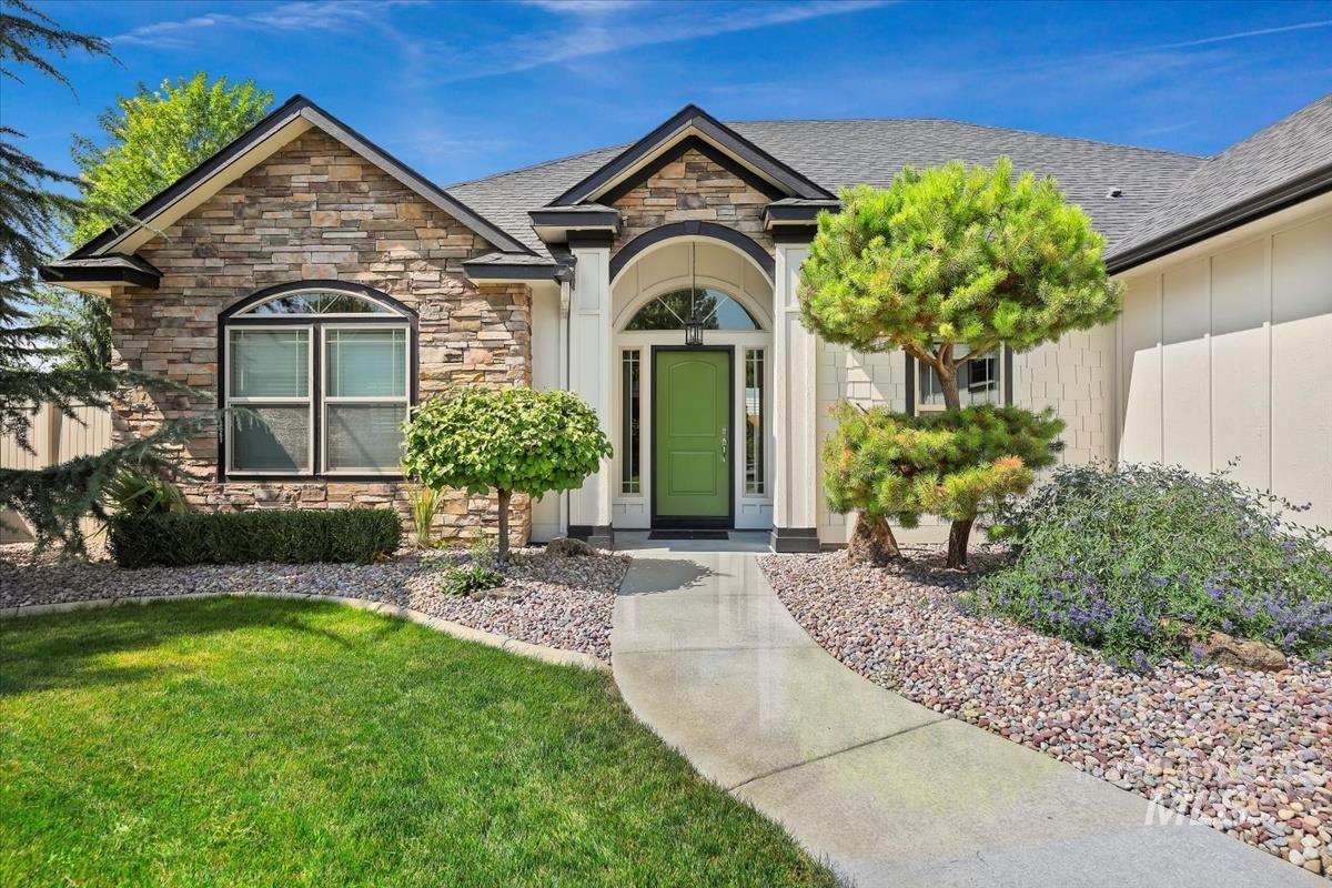 Doorway to property featuring stone siding, a yard, and a shingled roof
